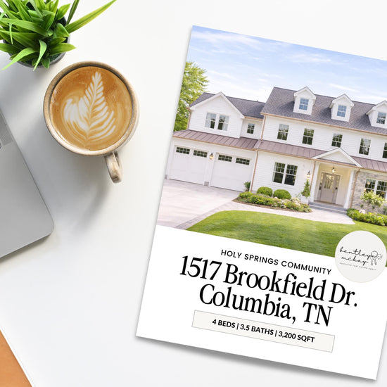 a brochure for a large two-story house in Columbia, Tennessee, with a laptop, coffee cup, and potted plant on a desk.